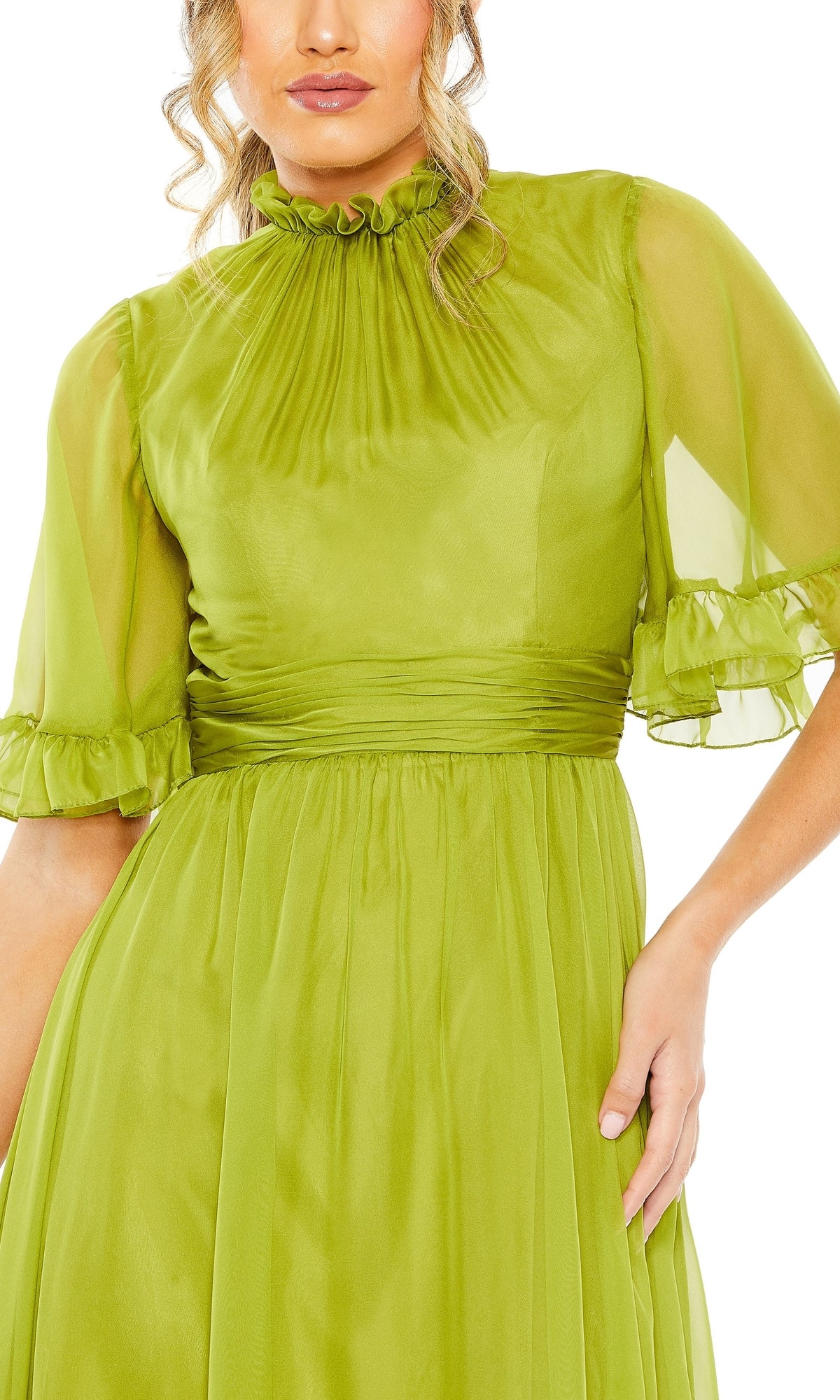 Woman wearing the Mac Duggal 68229 short sleeve long formal dress in light green, featuring a sheer high neck, ruffled sleeves, and gathered waist, posing with one hand on her hip.